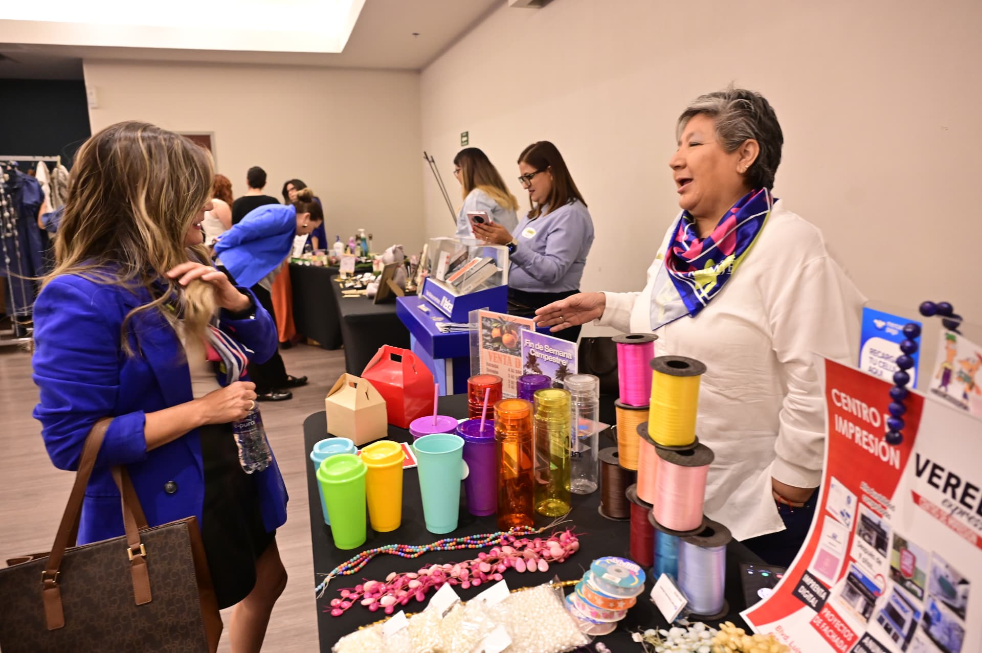 Stands de El Mercadito AMMJE con productos de emprendedoras en el desayuno empresarial de abril de 2026
