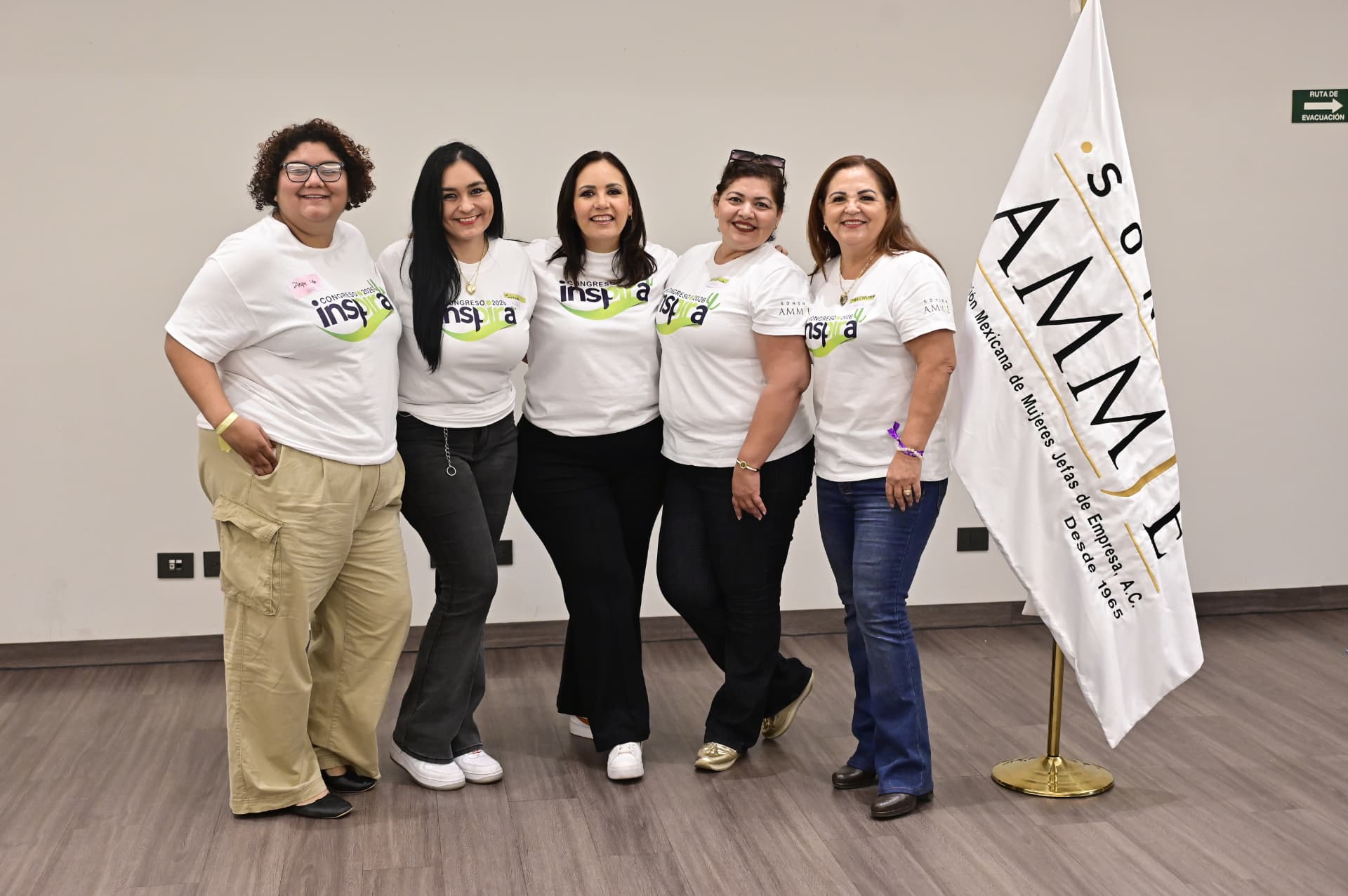 Socias de AMMJE Sonora posando junto al lábaro de la asociación en el desayuno de julio de 2026